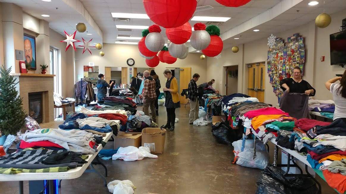 Photo shows multiple rows of clothing lining either side of a room, as members of the community look through them during a clothing swap in Knoxville, TN during 2019