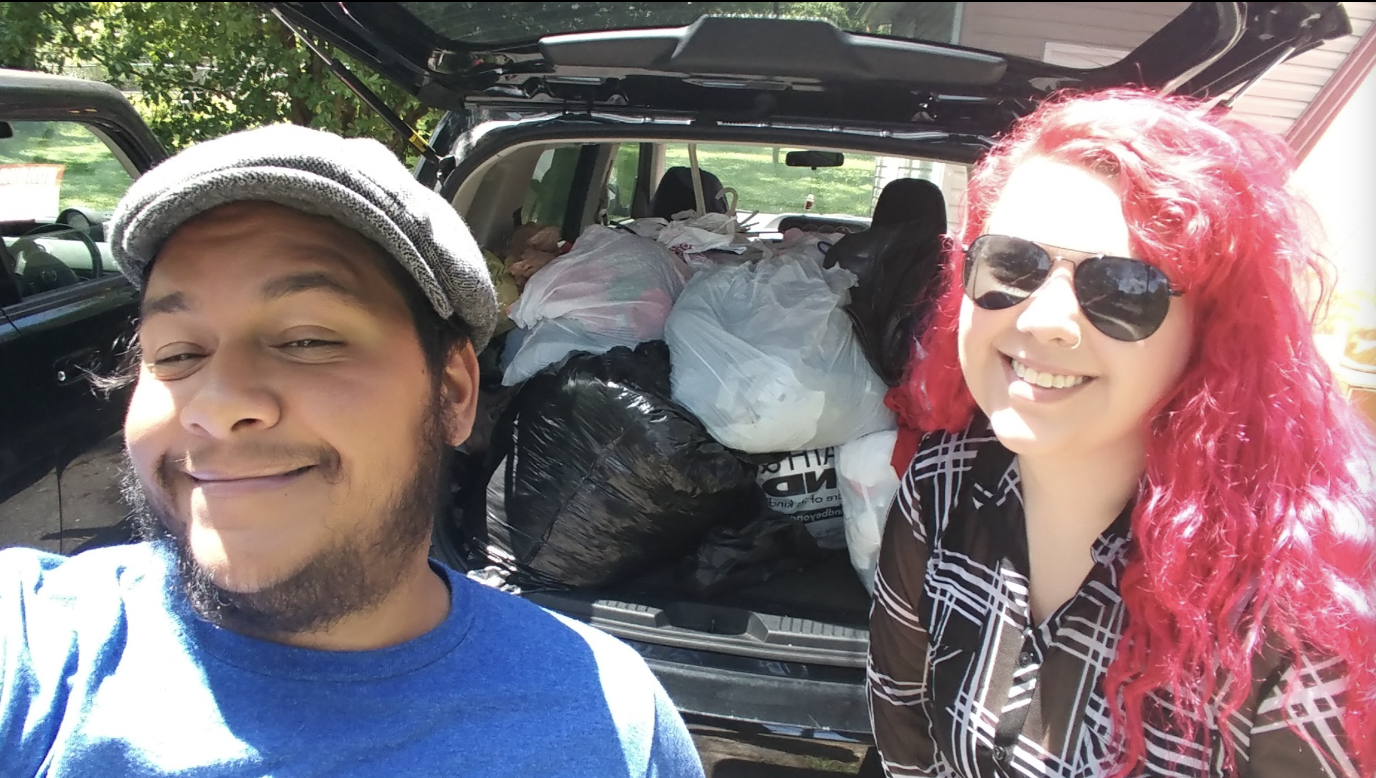Photo shows Jack Knoxville posing with a volunteer posing in front of a completely packed car full of clothing donations for the community, in 2017