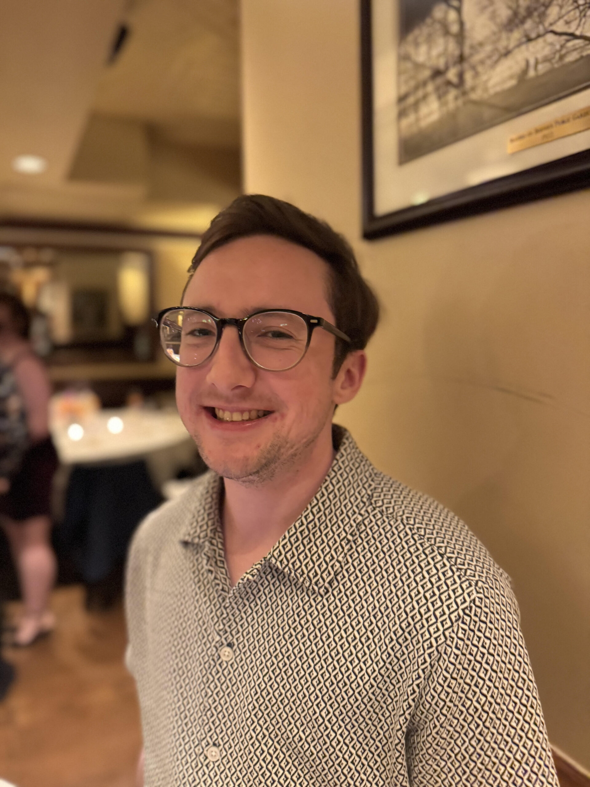 Robin is a light skinned male seen smiling. He has short dark hair which is neatly styled and is wearing glasses along with a button up shirt.